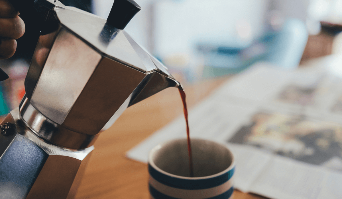 Melhor cafeteira italiana: veja os 7 melhores modelos. A imagem mostra uma cafeteira do tipo moka servindo café em uma xícara